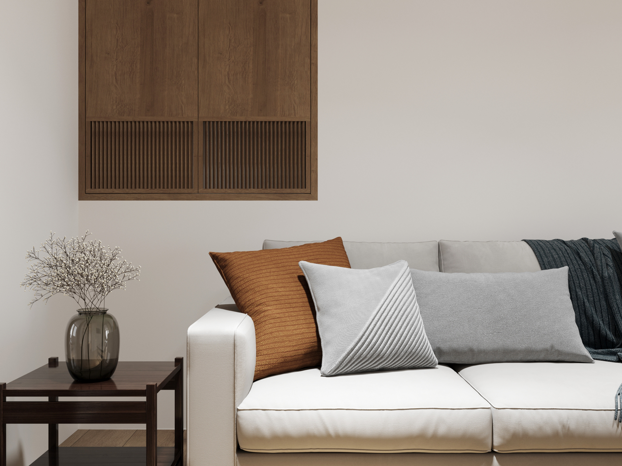 Sofa with rust and grey cushions beside a dark side table, under a timber wall cabinet.
