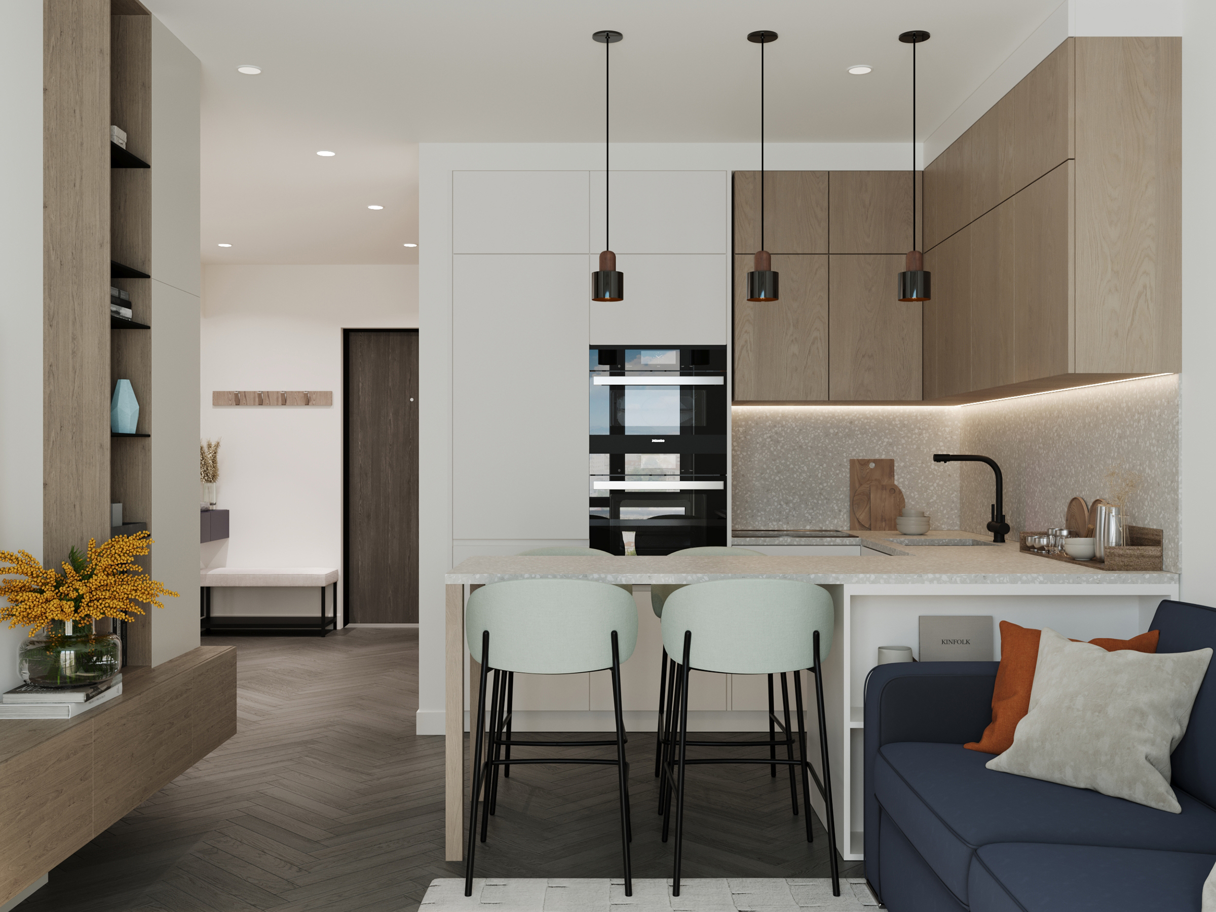 Open-plan kitchen and living room, with pendant lights over the island and a navy sofa.